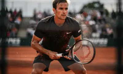 Carlos Alcaraz preparing to serve during a 2026 clay court tennis match under bright afternoon sun